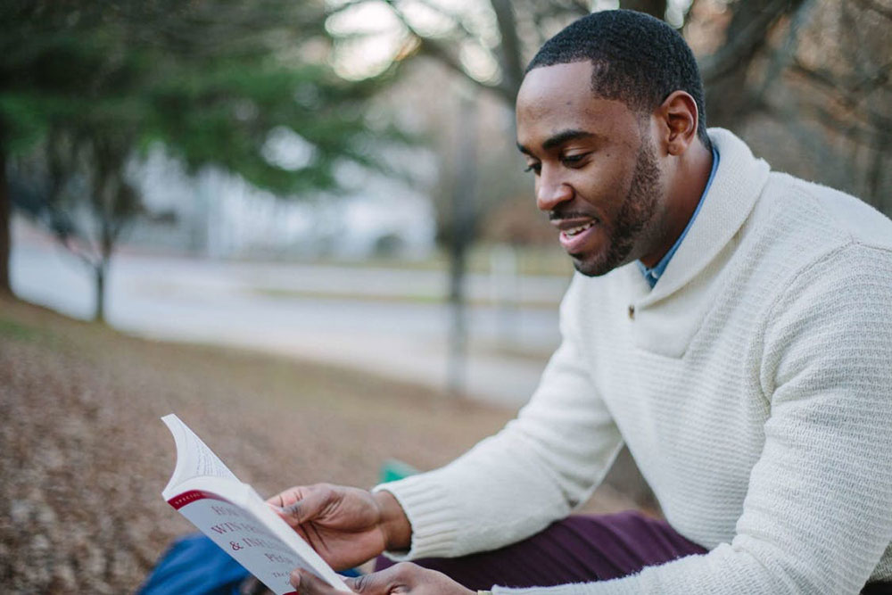 Man reading how to win friends and influence people at park