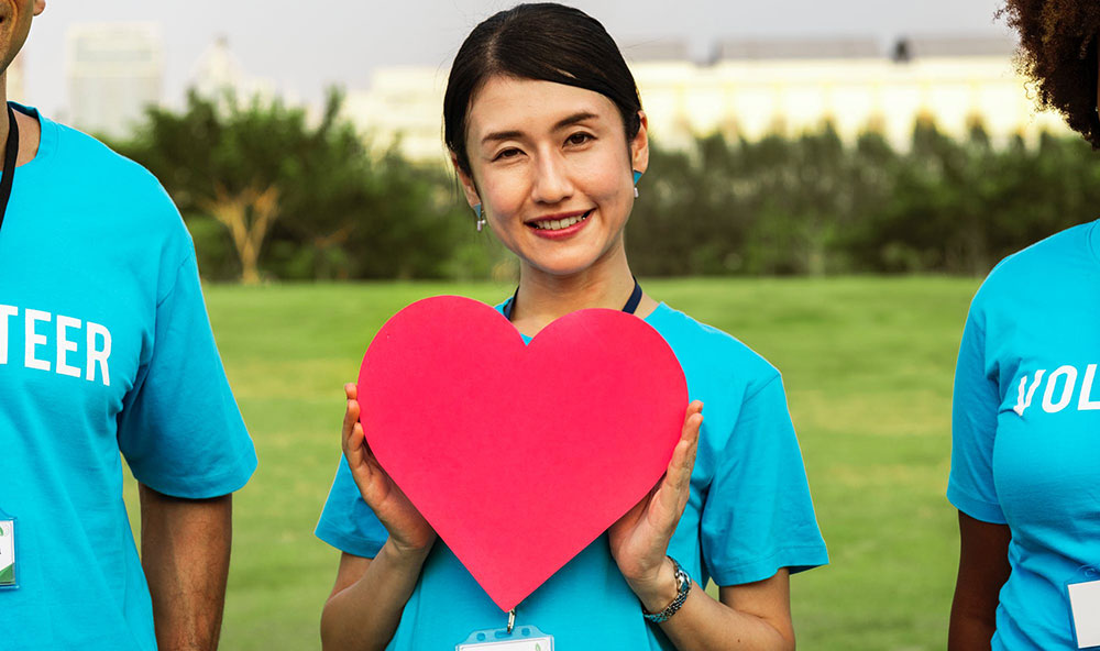 Asian woman holding up red heart cutout