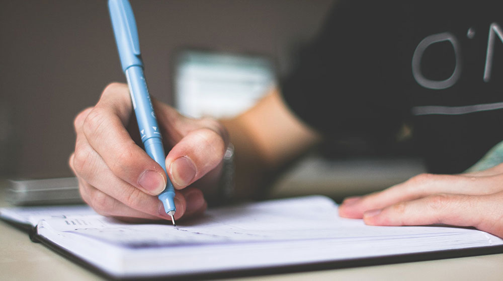 Person writing using pen and paper