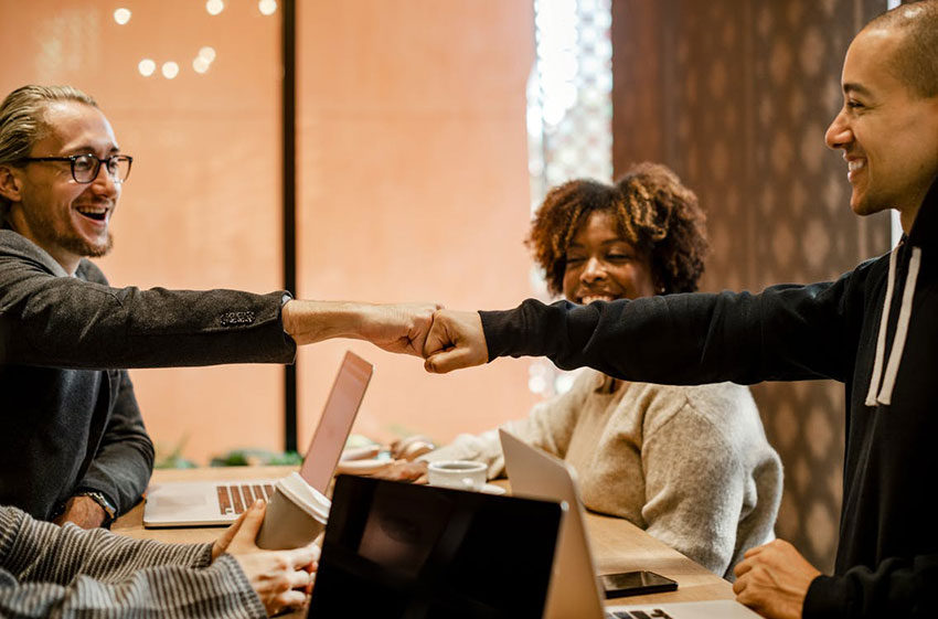 Business people fist bumping at table