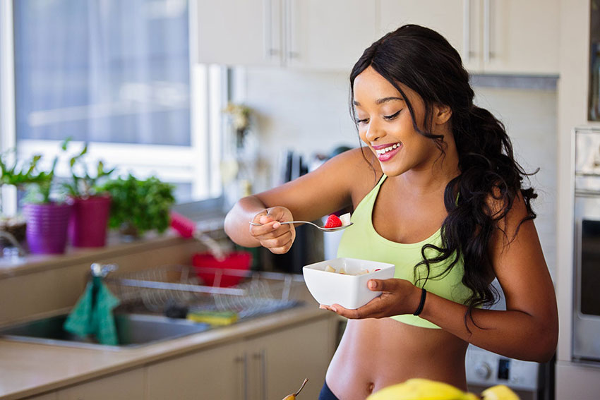 Woman in sports wear eating healthy bowl of food after workout
