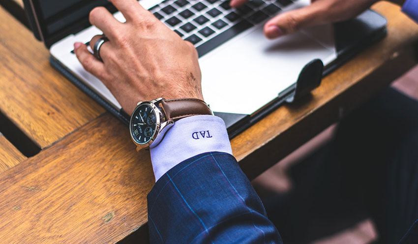 Man wearing watch working on laptop