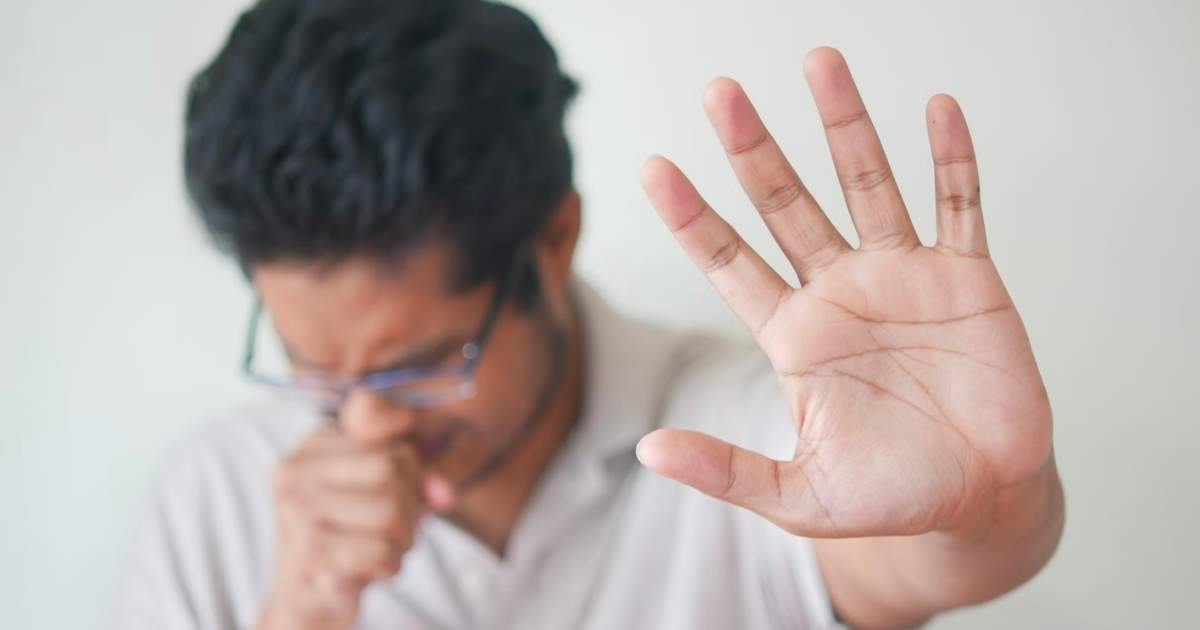 man coughing with his palm outstretched