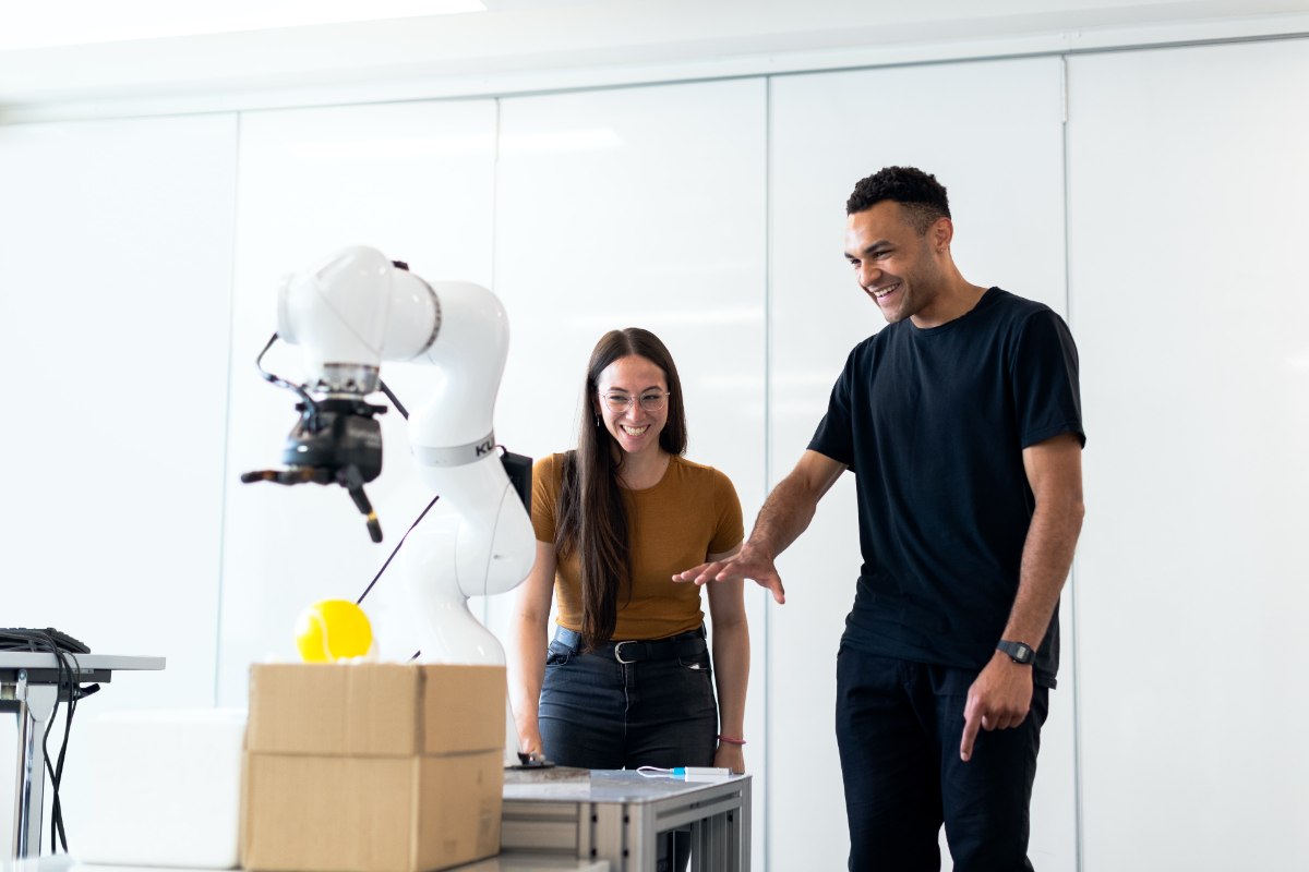 two people looking at a robotic arm