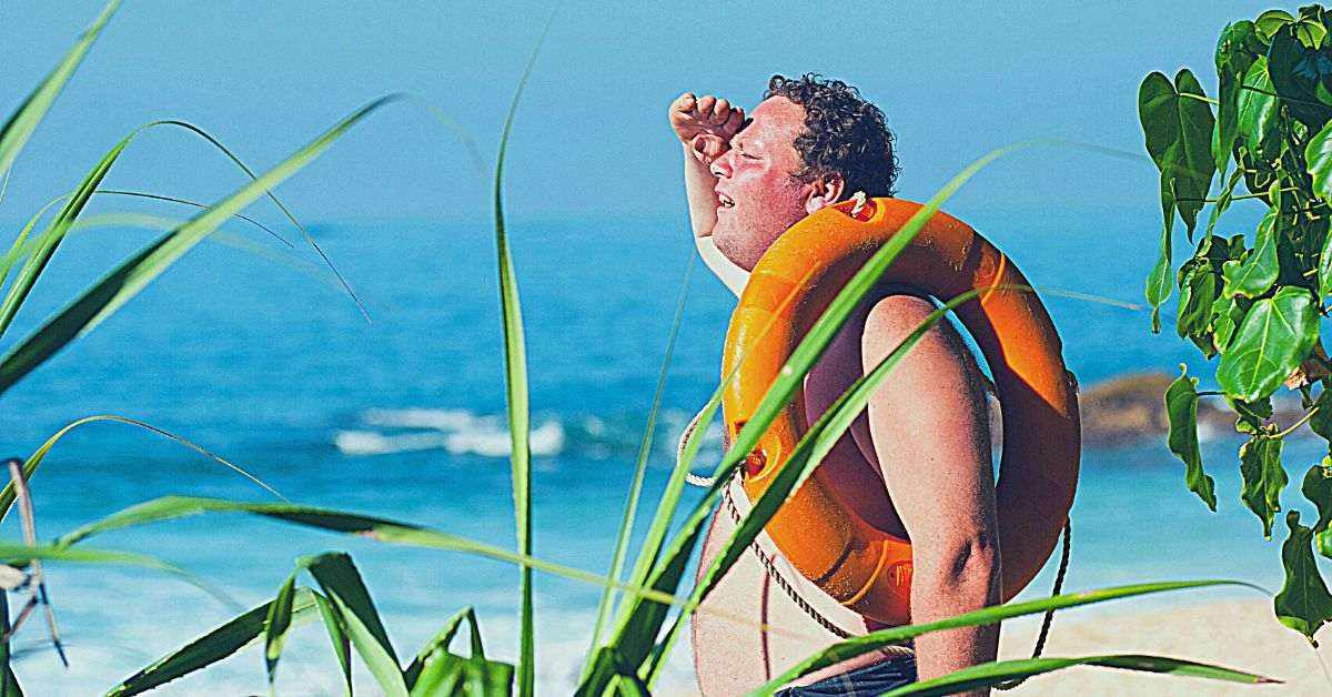 man in beach holding an orange floating device