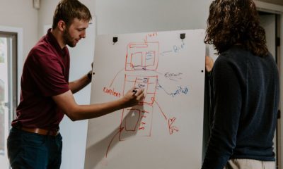 two people writing on a whiteboard