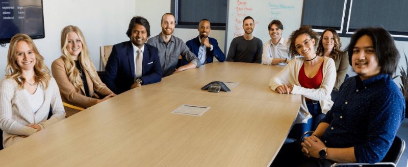 People smiling around a desk coworkers